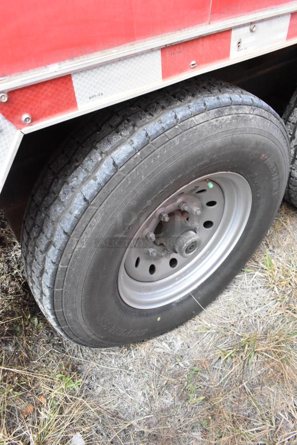 Close-up of a tire on a 28' Wendy's Fast Food Trailer. Visible reflective red and white striping above, indicating roadside visibility.