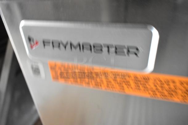 Blurry close-up of Frymaster label on commercial-grade kitchen equipment. Part of Rock Solid Cargo fast food trailer setup.