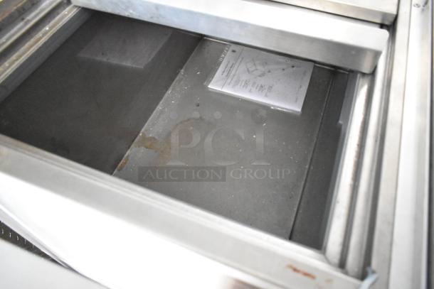 Interior of Rock Solid Cargo 24' mobile kitchen with metal storage compartment and visible food service documentation on the bottom.