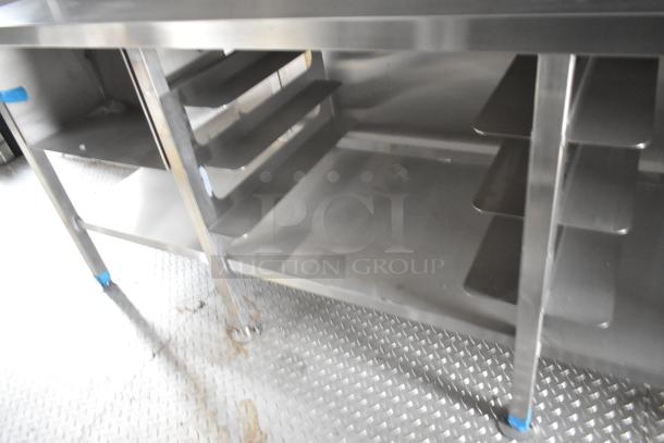 Commercial stainless steel storage shelving in a mobile kitchen trailer. Features multiple shelves on diamond plate flooring.