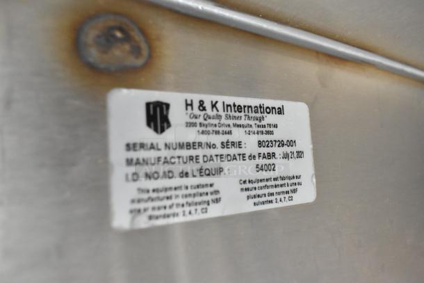 Metal surface with H&K International tag showing serial number 8023729-001 and manufacture date of July 21, 2021.
