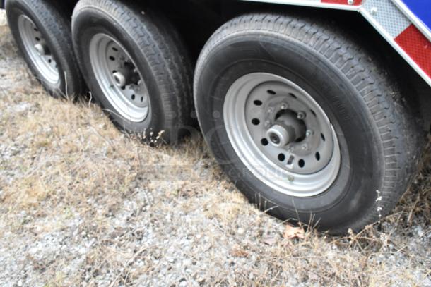 Four wheels of a Rock Solid Cargo trailer on gravel, showcasing heavy-duty tires and alloy rims, perfect for mobile kitchen use.