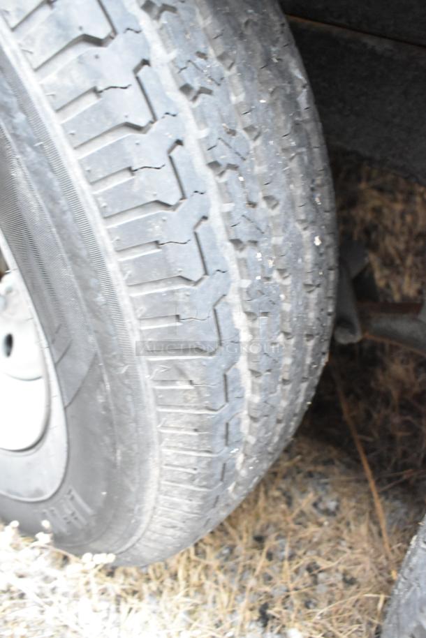 Close-up of a tire on a Rock Solid Cargo 24' trailer, featuring tread and rubber details, indicating its used condition.