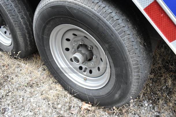 Close-up image of a tire from a Rock Solid Cargo 24' mobile kitchen trailer. Tire markings include "LH-001." Trailer features commercial-grade kitchen equipment.