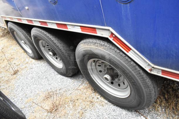 Blue Rock Solid Cargo trailer with triple axles, Ridgway Sport ST tires, and reflective red and white safety stripes.