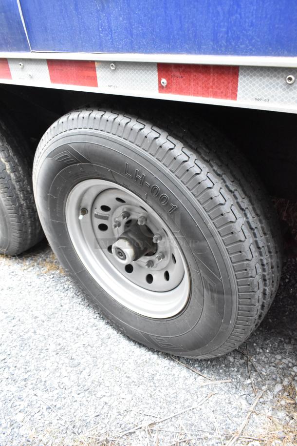 Rock Solid Cargo trailer tire, labeled LH-001, mounted on dual axle setup. Features reflective stripes for visibility.