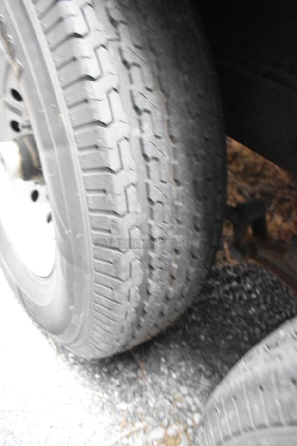 Close-up of black tire with textured tread on a Rock Solid Cargo 24' fast food trailer, condition appears used.