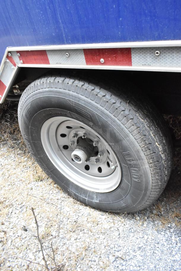 Close-up of Rock Solid Cargo trailer tire with LH-001 marking. Featured blue exterior with silver and red trim.