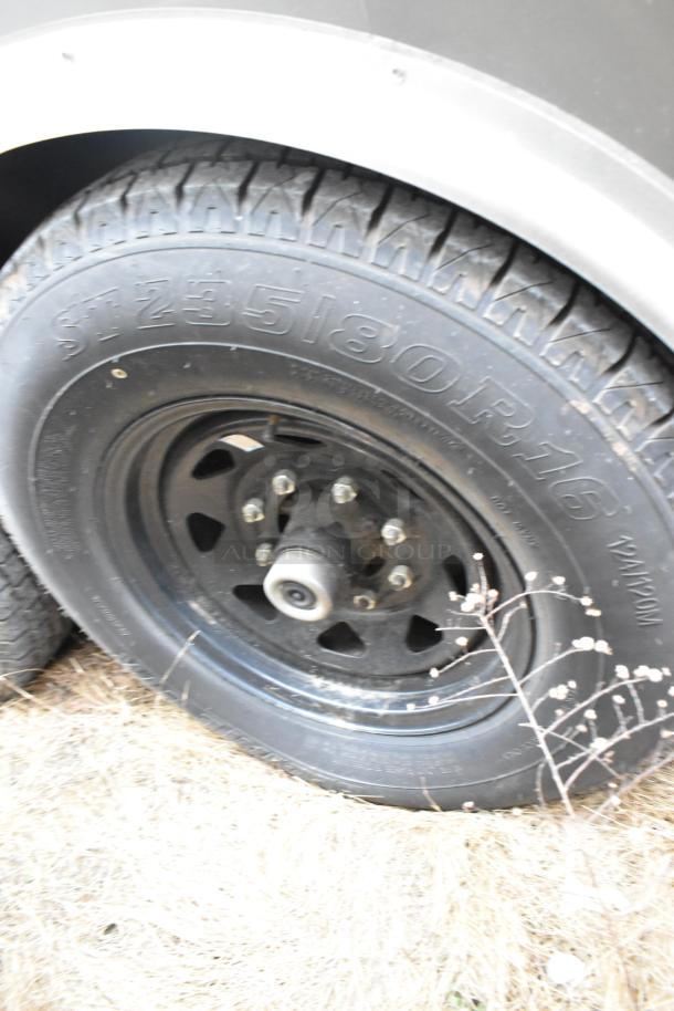 Close-up of a black tire on a Nationwide 24' food trailer. Tire markings visible, indicating size ST235/80R16.