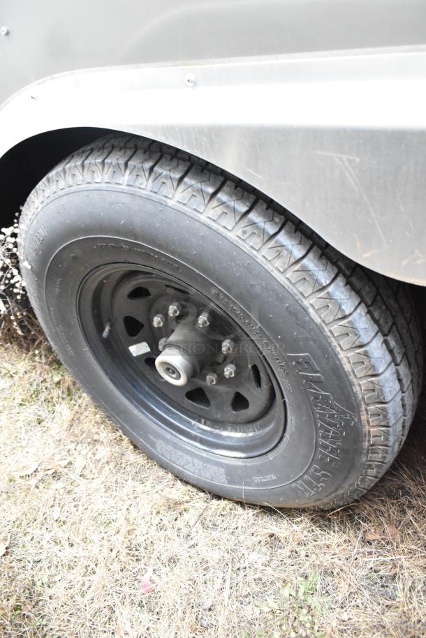 Close-up of a tire on a Nationwide 24' food trailer, showing tire tread and wheel rim in outdoor setting.