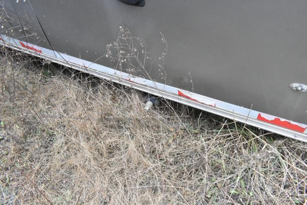 Close-up of a Nationwide 24' food trailer exterior with worn red and white reflective tape, showing ground vegetation.