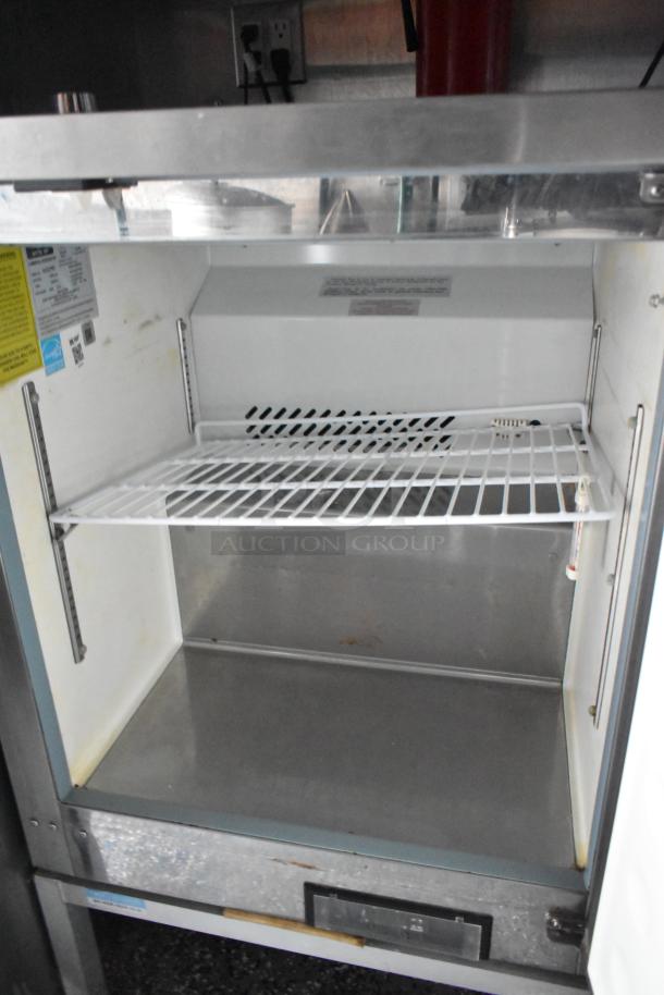 Open commercial cooler interior inside a Stuff4less 24' mobile kitchen, featuring a wire shelf and metal base.