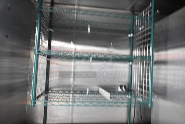 Interior of a Stuff4less 24' food trailer showing green metal shelving, electrical outlet, and stainless steel walls.