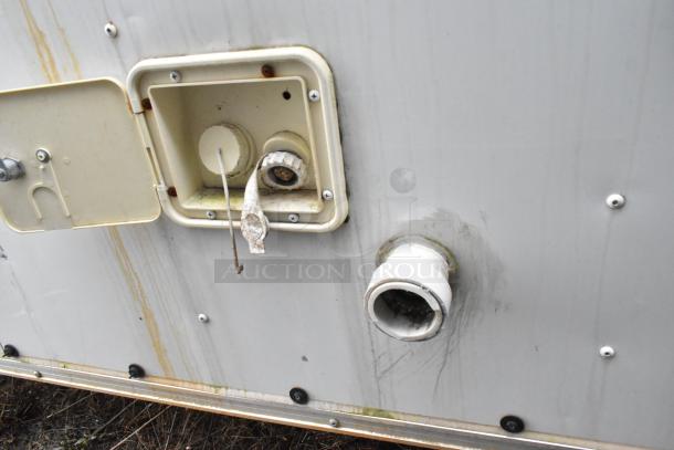 Exterior panel of Stuff4less 24' fast food trailer with utility access ports and piping connections, showing some wear.