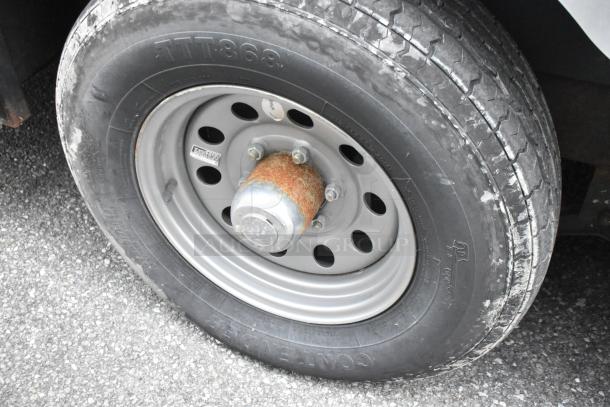Close-up of a tire on the Stuff4less 24' shell food trailer, showcasing its metal wheel rims with some rust and visible tread.