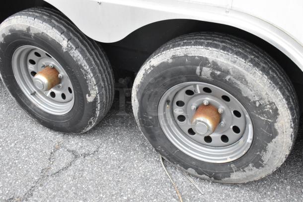 Close-up of dual wheels on a 2019 Stuff4less 24' food trailer. Tires show wear; hubs appear rusted. Trailer sold with a clear title.