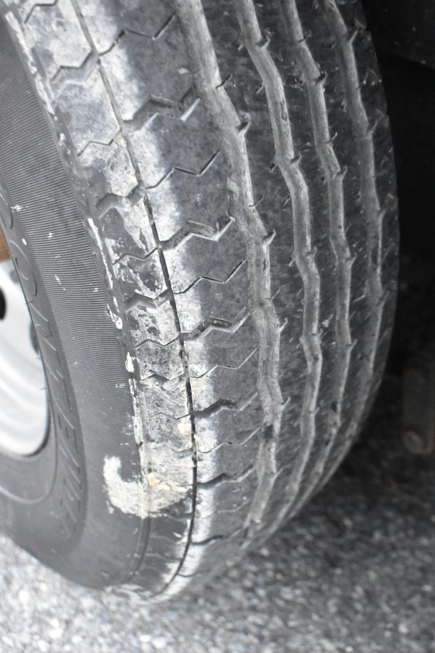 Close-up of tire tread on a Stuff4less 24' food trailer. Tire appears in good condition, ready for road use.