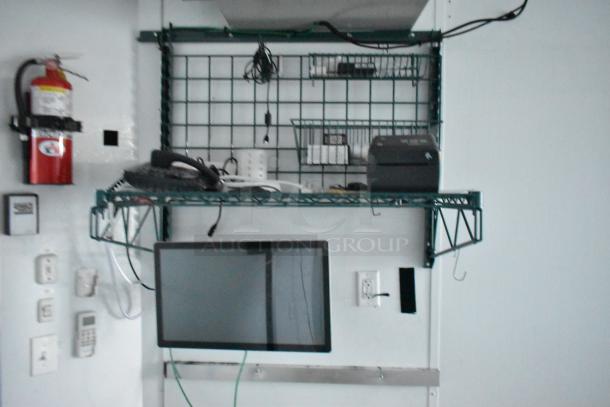 Interior view of unbranded SDG 20' food trailer. Features shelving, mounted monitor, electrical outlets, and fire extinguisher.