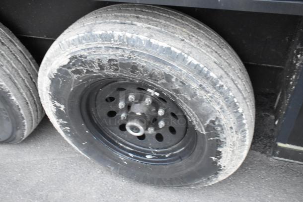Close-up of a wheel on a 2020 SDG 20' unbranded shell food trailer, showing a black rim and weathered tire.