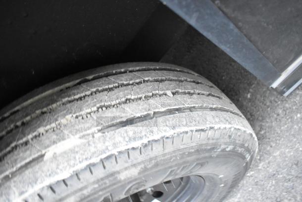 Close-up of a worn tire from the SDG food trailer, showing significant tread wear, mounted on a metal rim.