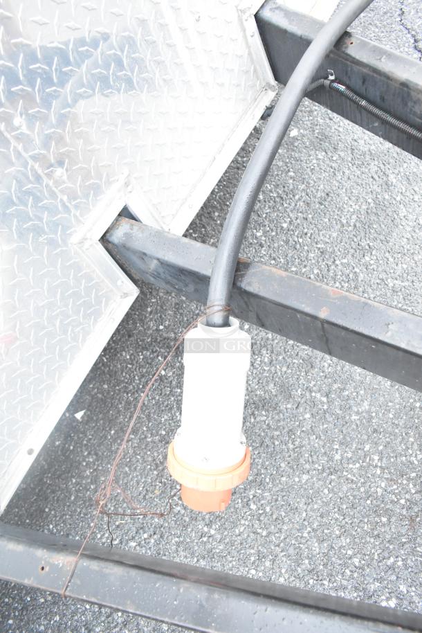 Power connection detail of a Stuff4less 24' mobile kitchen trailer, showing plug and diamond plate siding.