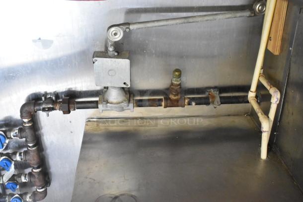 Interior plumbing and fixtures of a Stuff4less 24' unbranded shell food trailer, featuring metal pipes and connectors.