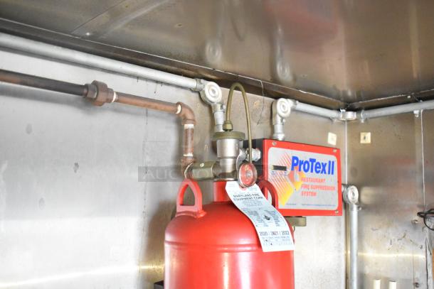 Interior of Stuff4less food trailer, featuring a ProTex II fire suppression system with attached label and piping.