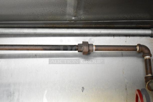 Close-up of piping inside a Stuff4less 24' unbranded shell food trailer. Visible are metal pipes and connectors against a stainless steel backdrop.