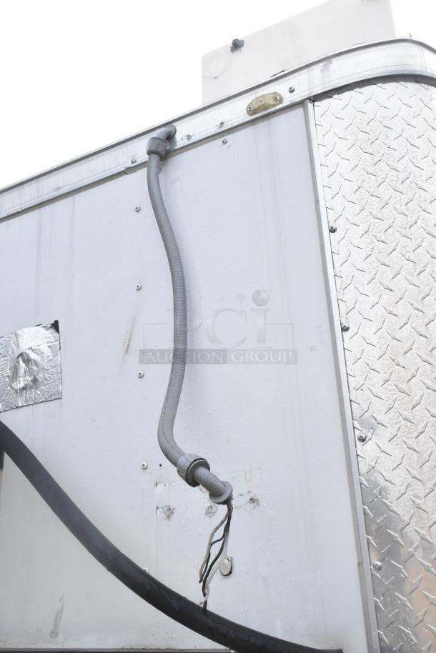 Exterior view of Stuff4less 24' fast food trailer showing metal siding and utility connections, part of a fully equipped kitchen setup.
