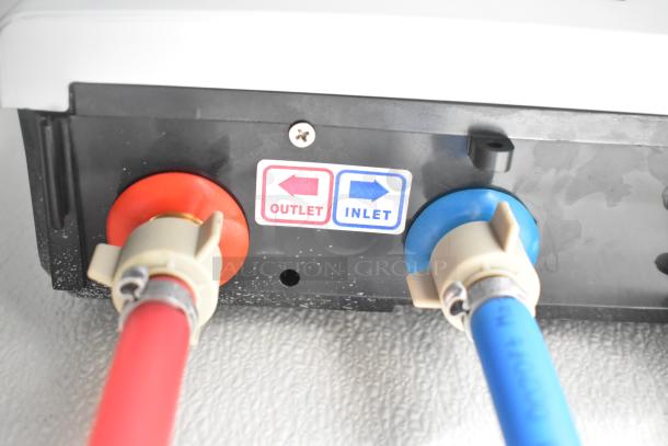 Close-up of outlet and inlet connectors on a Nationwide 24' cold food trailer. Red and blue labels indicate flow direction.