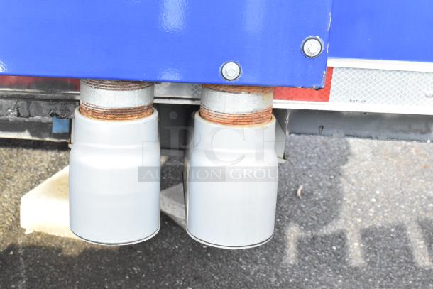 Close-up of two exhaust pipes beneath a Rock Solid Cargo mobile kitchen trailer, indicating its new condition.