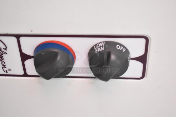Control knobs on a Coleman appliance, featuring temperature and fan settings, labeled "Low Fan" and "Off."