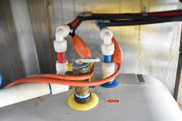 Close-up view of plumbing connections inside Rock Solid Cargo fast food trailer, featuring pipes and fittings.