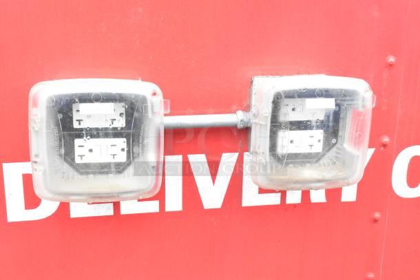 Red exterior of Rock Solid Cargo trailer with two weatherproof clear outlet covers.