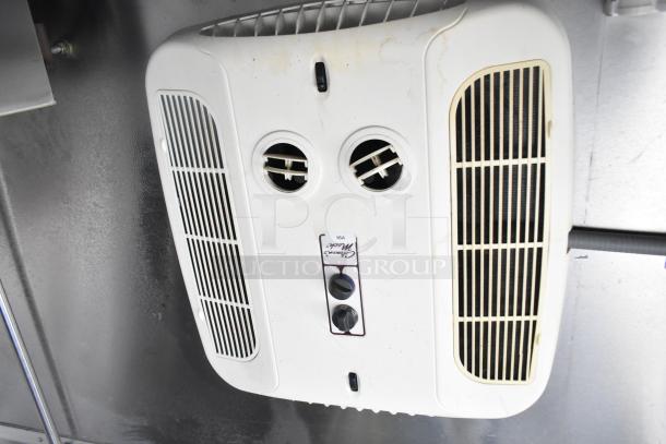 Ceiling-mounted white air vent in mobile kitchen trailer, featuring dual circular vents and labeled "Coast to Coast."