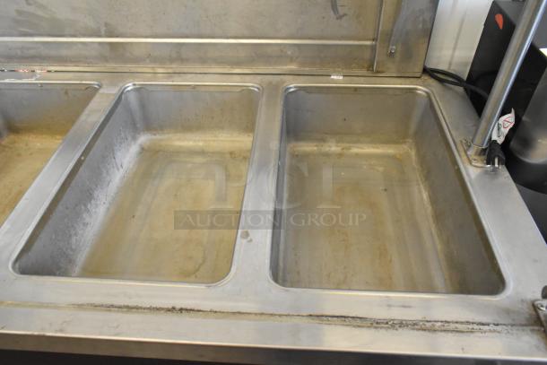Stainless steel 4 well heated buffet station with tray slide, glass over shelf, visible wear, ideal for commercial use.