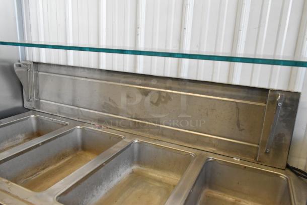 Stainless steel commercial 4 well heated buffet station with tray slide and glass over shelf, used condition.