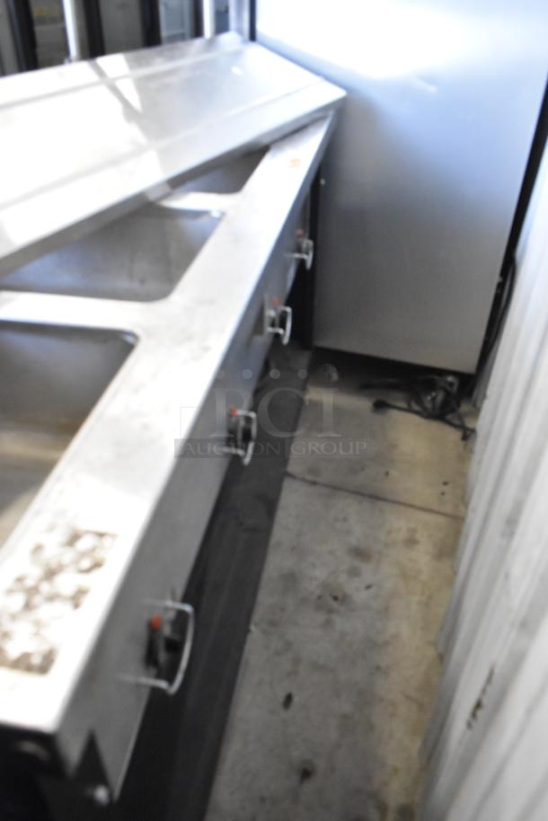 Stainless steel 4-well heated buffet station with tray slide and glass over shelf, showing moderate wear.
