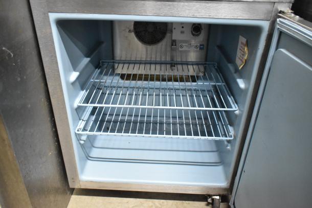 Delfield 406CA stainless steel undercounter cooler, single door, missing one caster, 115V, interior shelves visible.