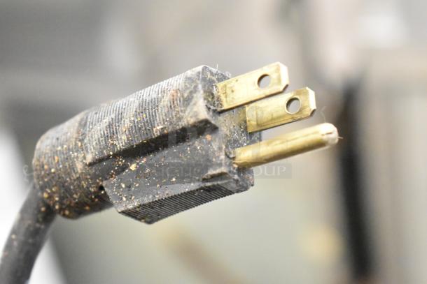 Close-up of a dusty power plug for a Carter Hoffmann MC212S2-2DD commercial heated holding cabinet, 120V, 1 phase.