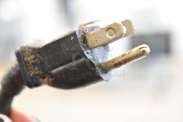 A close-up of a worn two-prong power plug with visible dirt and slight rust, part of a Hatco heated holding cabinet.