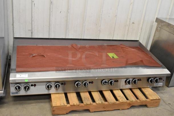 Garland stainless steel commercial countertop flat top griddle, brand new with scratch and dent. Multiple control knobs visible.