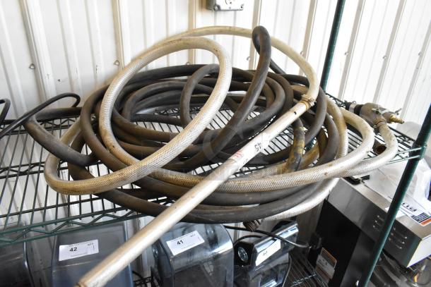 Coiled hoses on a metal shelf, including braided and rubber types. Visible label marked "45." Used condition.