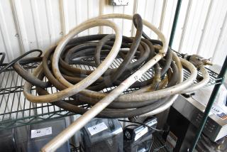 Coiled hoses on a metal shelf, including braided and rubber types. Visible label marked "45." Used condition.