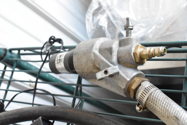 Close-up of two industrial hoses with metal connectors attached to a metal grid. The hoses appear to be in used condition.