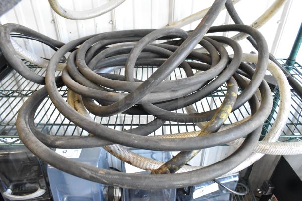 Coiled industrial hoses on a metal shelf, showing signs of wear; auction item offering two hoses per bid.