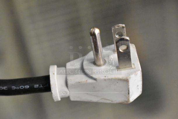 Close-up of a white electrical plug for the True GDM-12-LD cooler, showing three prongs and model markings.