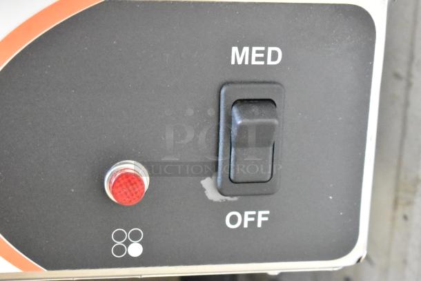 Control panel of Nemco 6311-4-240 hot plate, showing a medium heat switch and red indicator light on a black surface. Scratches visible.