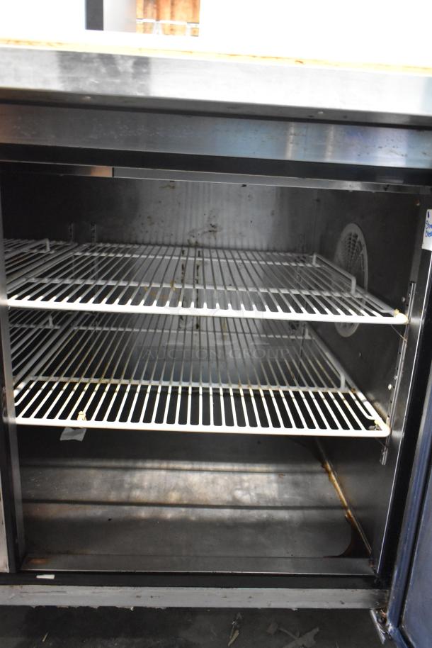2018 Atosa MPF8202GR stainless steel pizza prep table, two wire shelves, on commercial casters, minor wear visible.