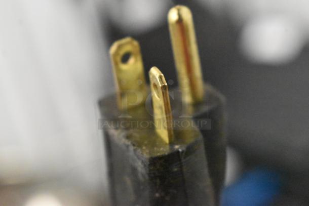 Close-up of a power plug from a Stoelting F131-38I2 ice cream machine, showing three brass prongs.
